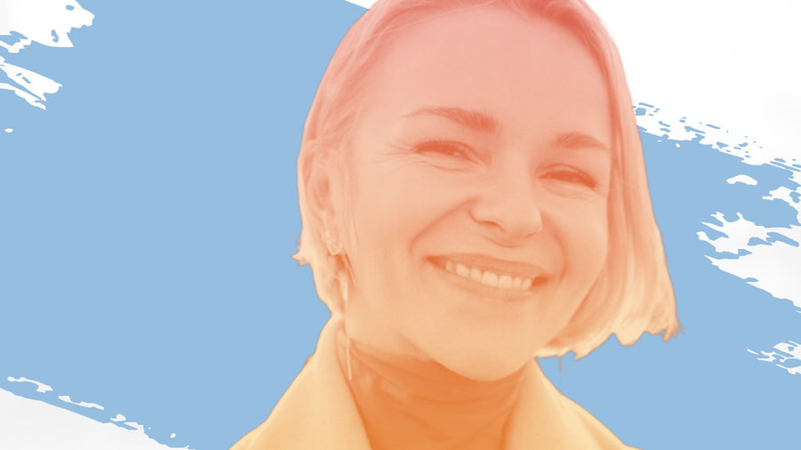 Smiling woman with short blonde hair in a mustard coat, for the BelleSkin article Facials for Dark Spots: Worth Your Money After 40, or Skip?